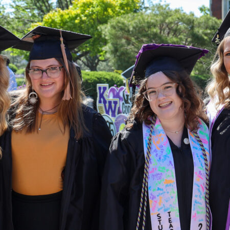 Group of graduates in cap and gown in front of Pioneer