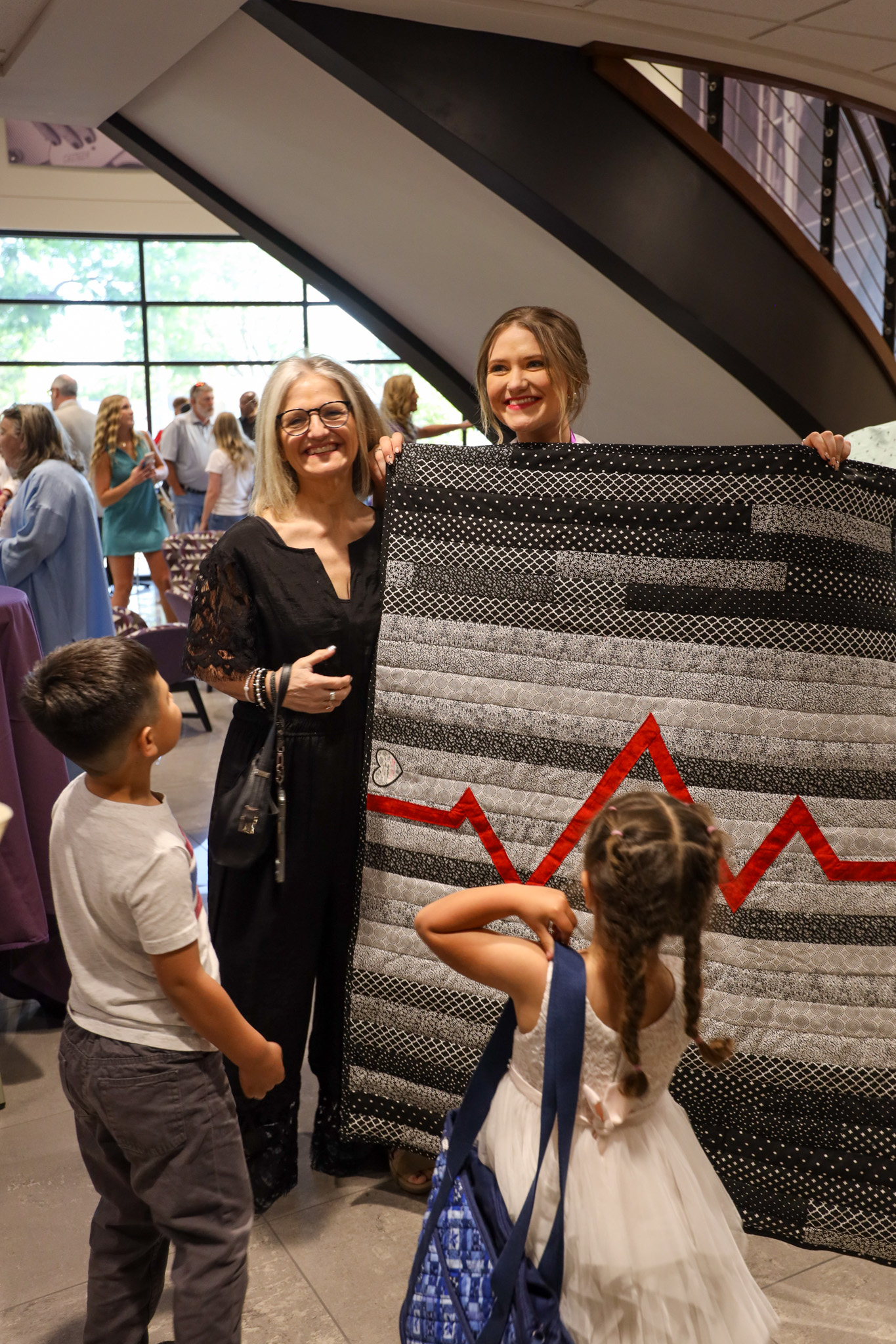 Nursing graduate holding blanket with heartbeat symbol with familu