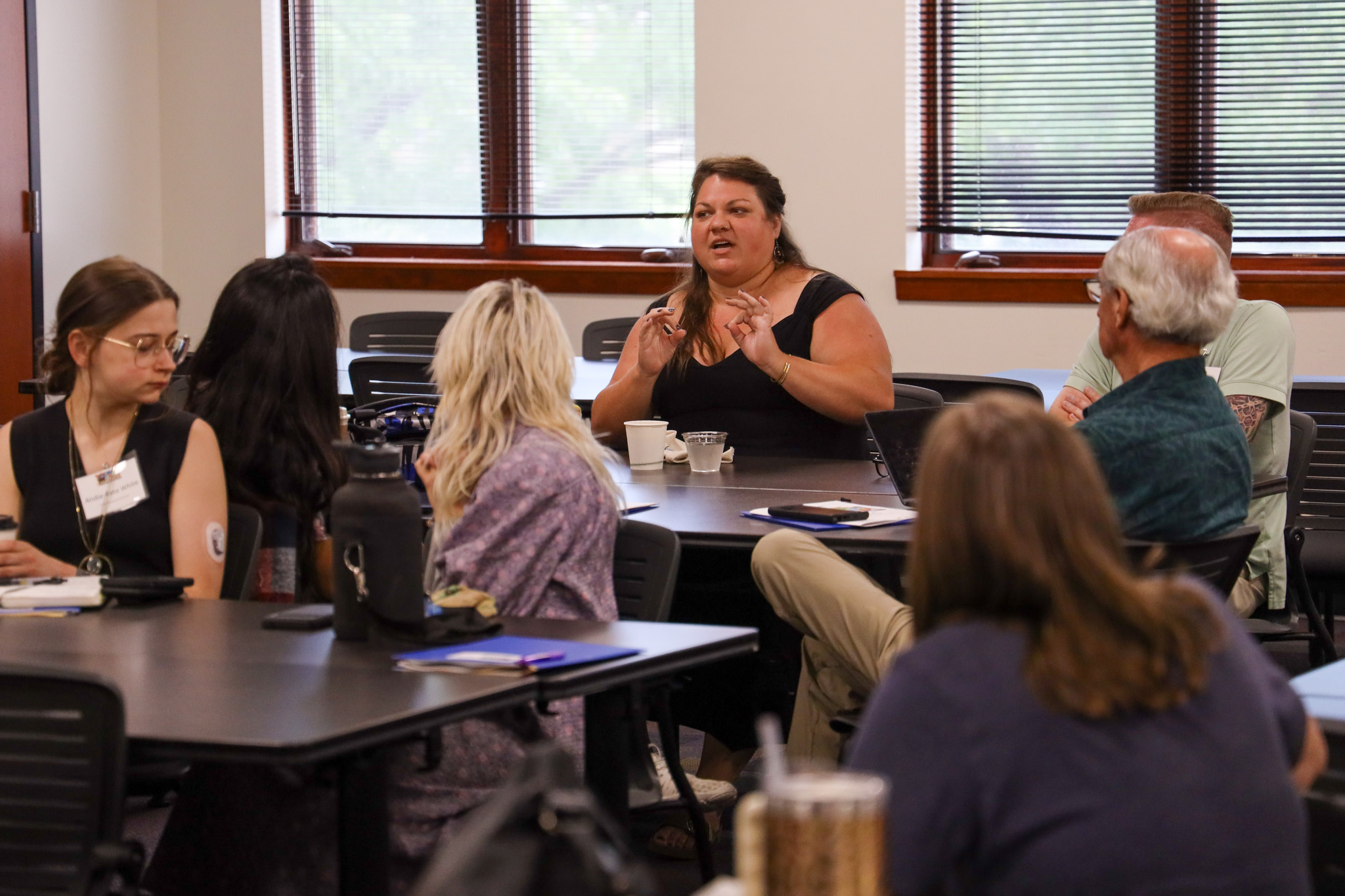 Woman sitting and gesturing in front of class