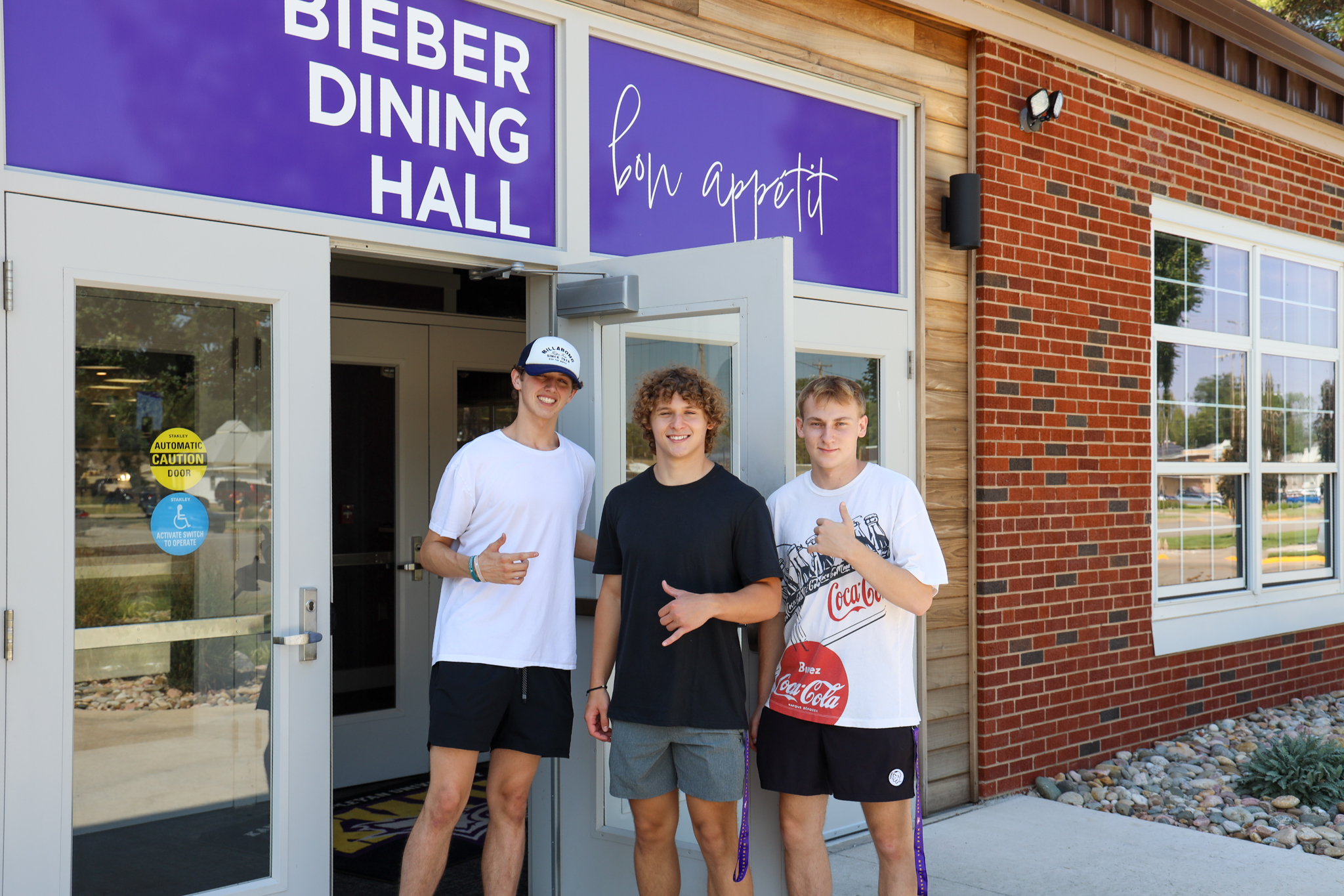 Three male students in front of dining hall