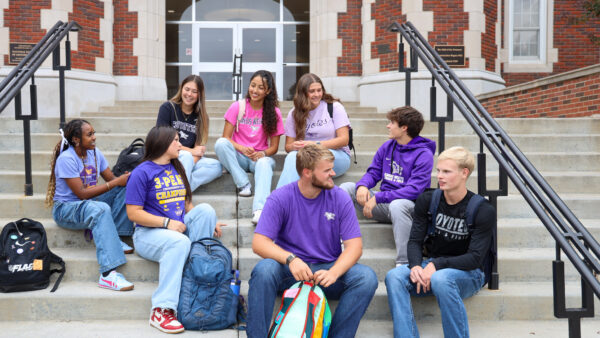 A group of students sit on the steps of Pioneer Hall.