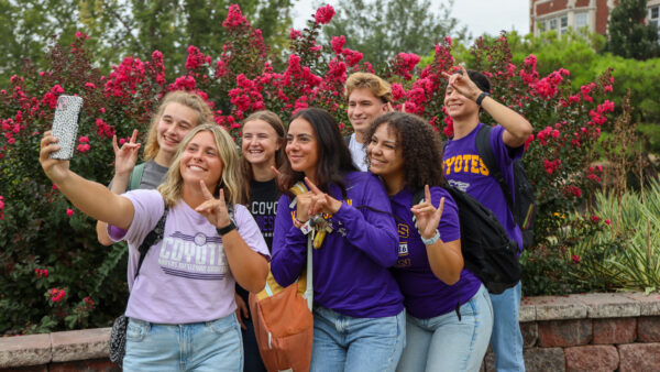 A group of students take a selfie on campus.