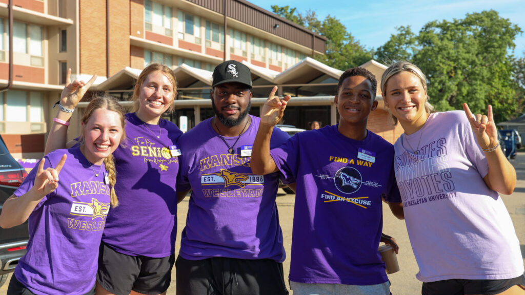 Five people standing in front of dorm during move-in doing Yote sign