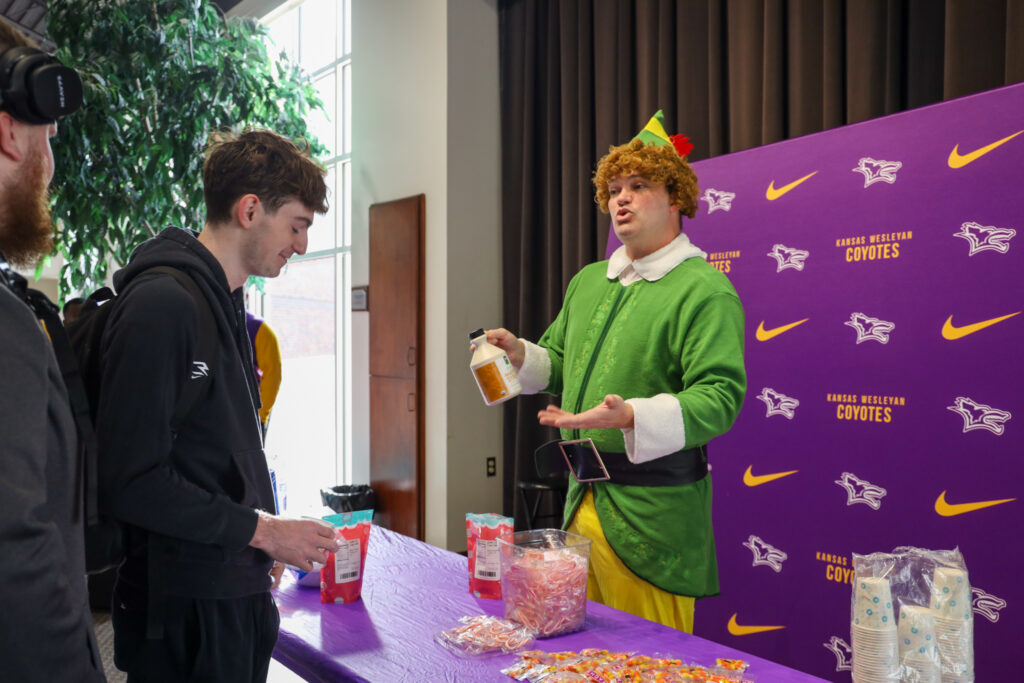 Man in elf costume talking to students
