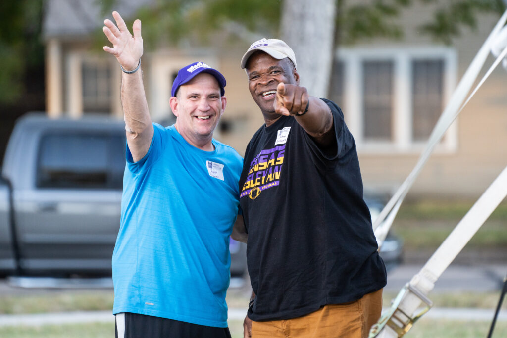Two men pointing and waving