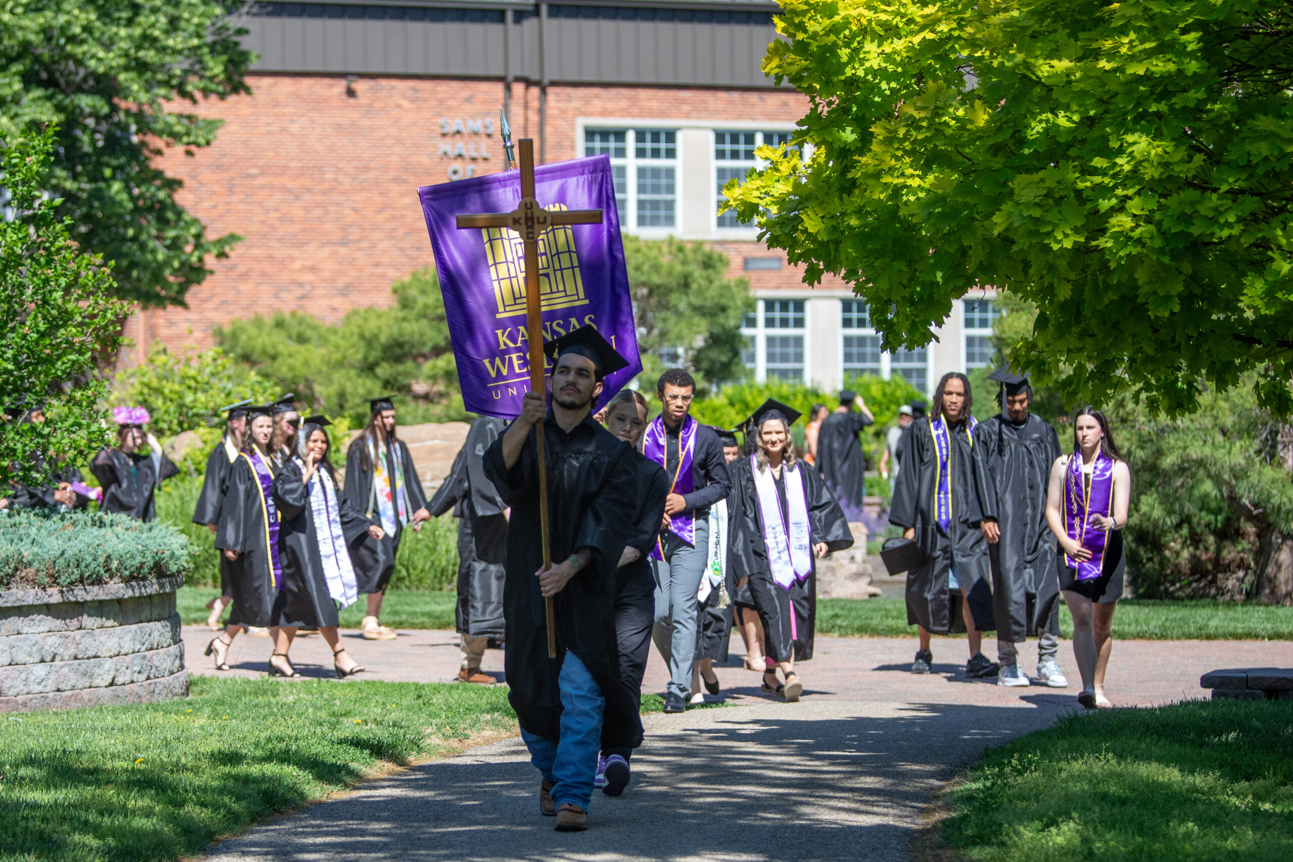 Man carrying university cross and leading large group