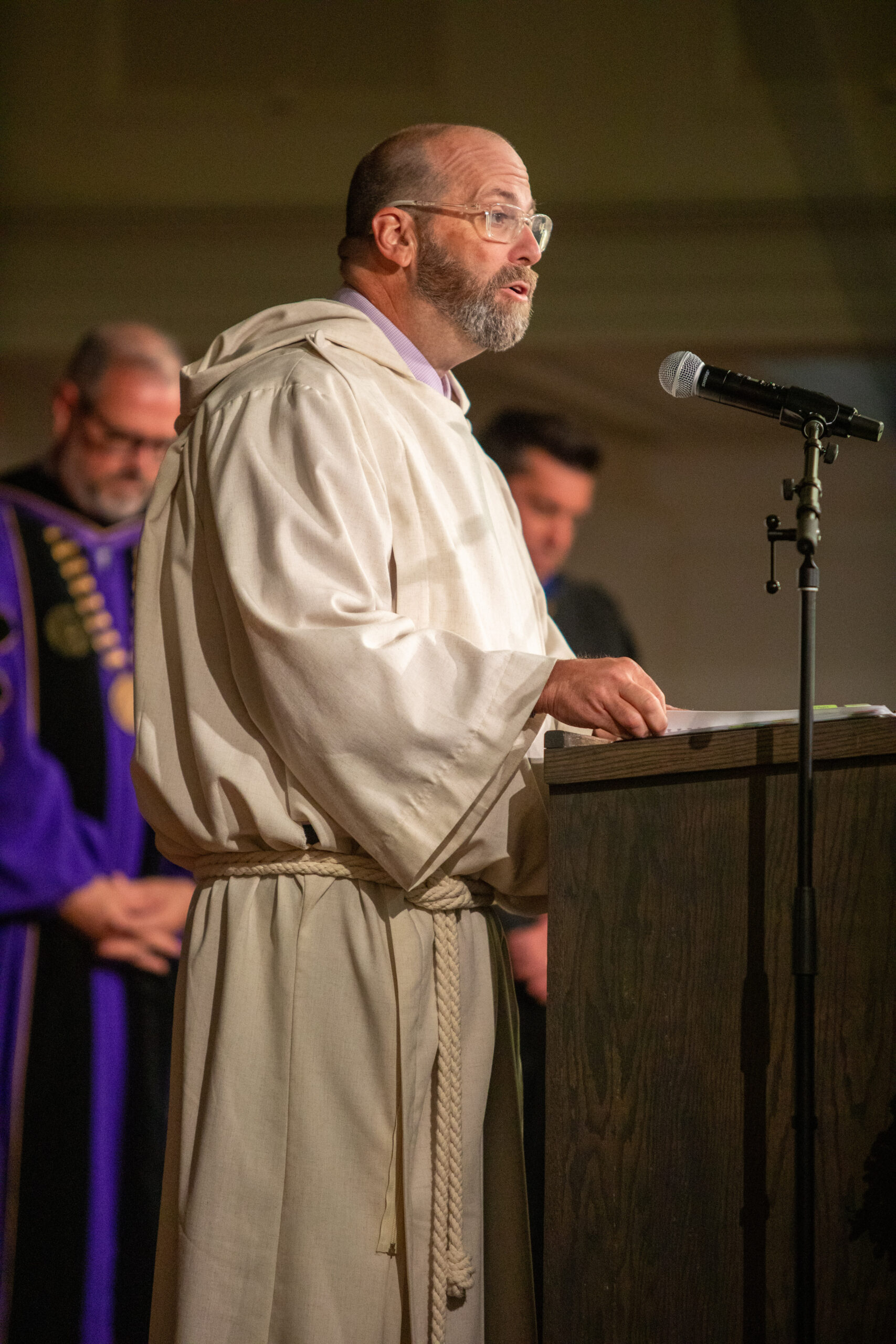 Man in clergy robes speaking at podium