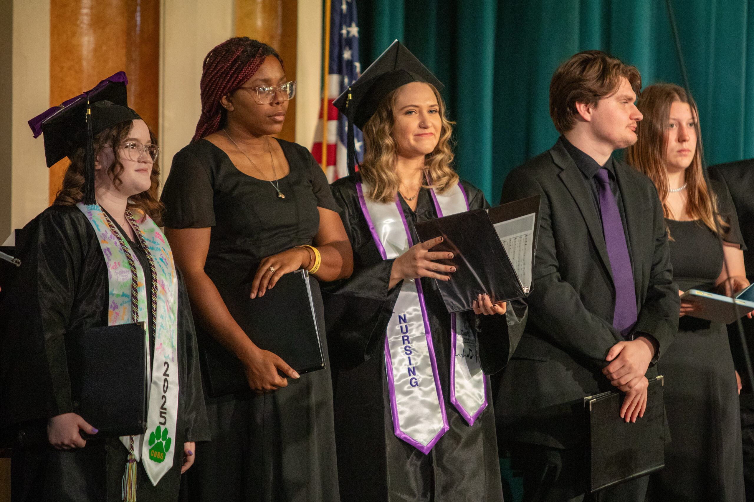 Small group in black robes singing, mostly women