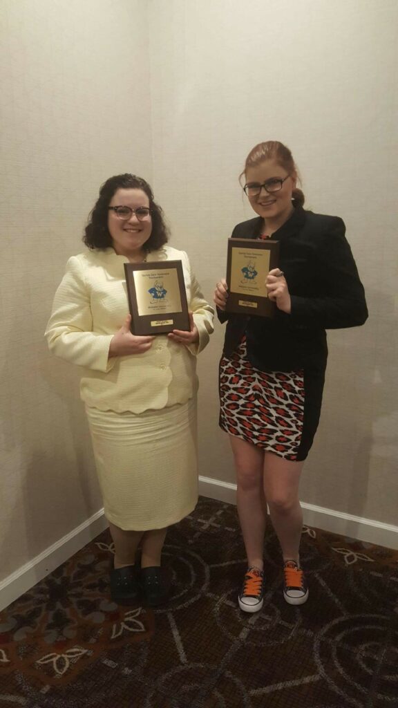 Two female students holding awards