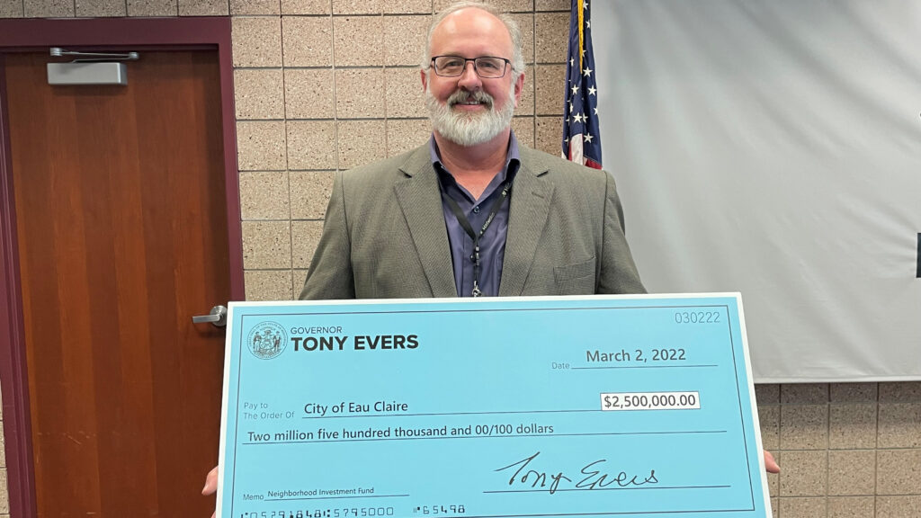Gray-haired man with beard holding check