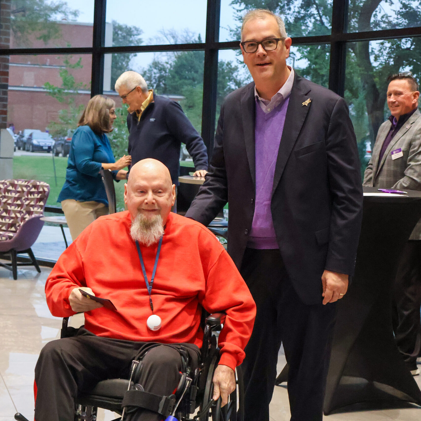 Man standing by man in wheelchair with award