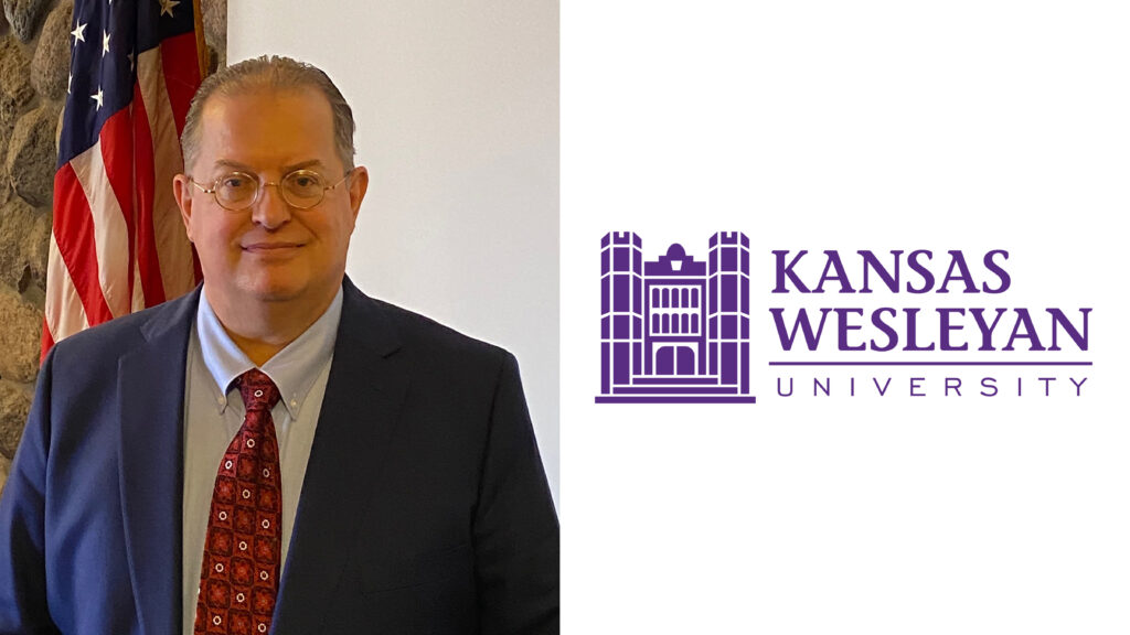 Man in suit in front of flag, university logo