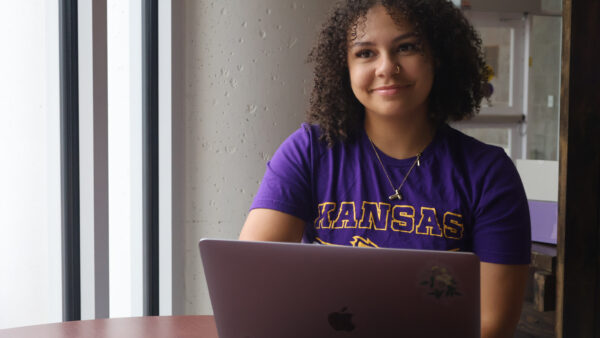 A student with a laptop poses for a photo.