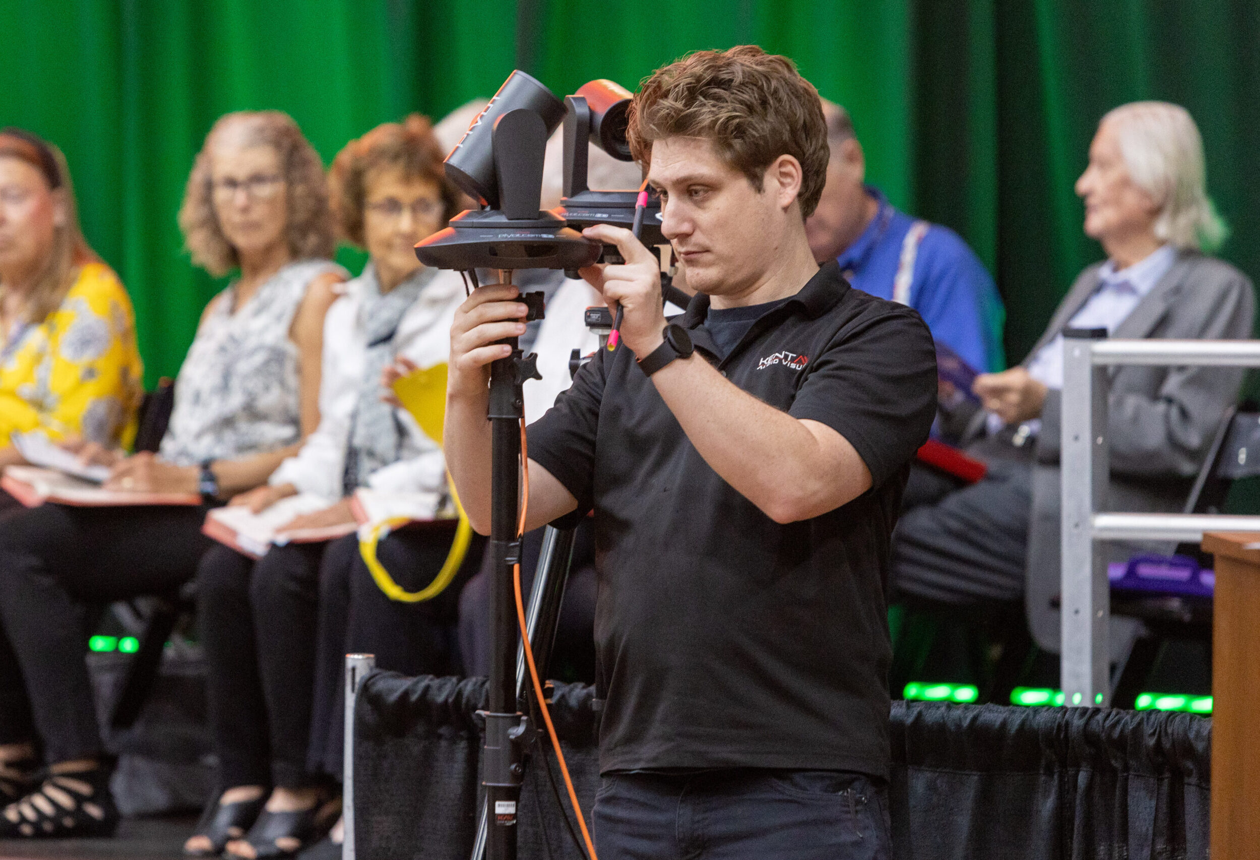 Man taking video with conference attendees behind