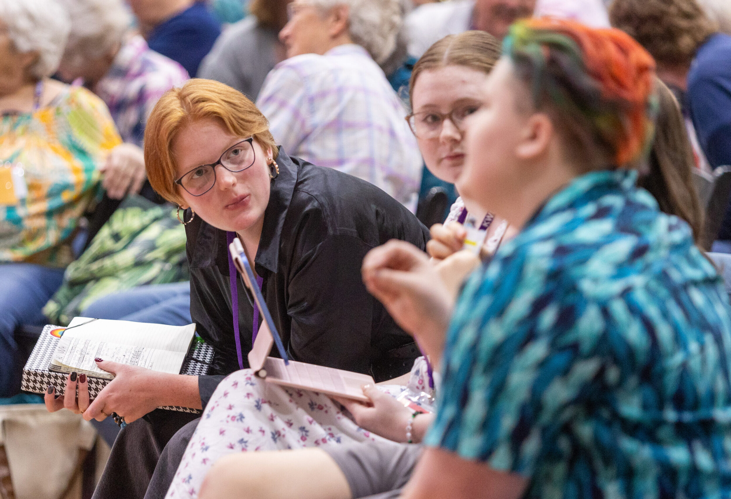 One person in crowd leaning over to talk down row to another